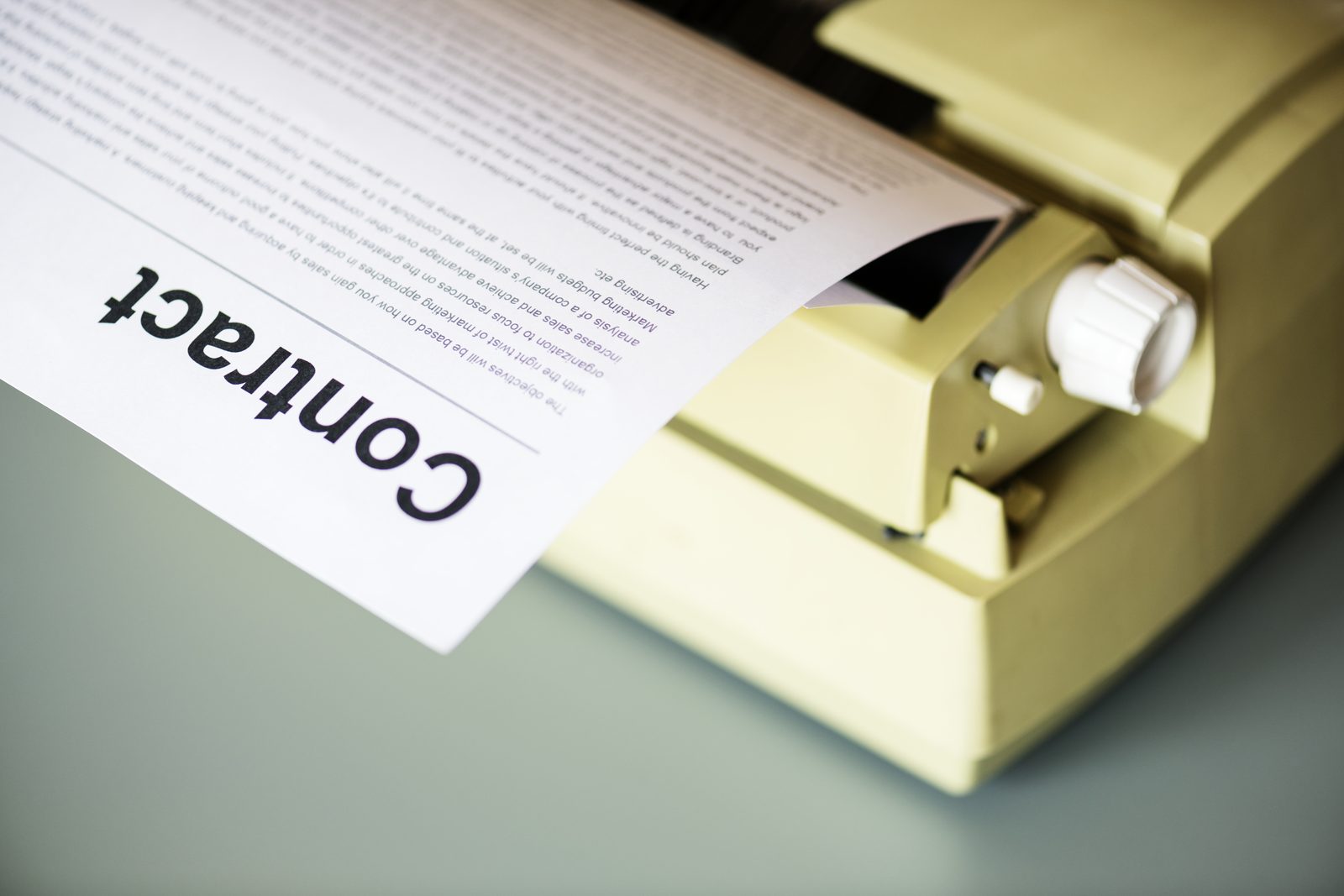 A document headed Contract feeding through a typewriter, representing the paperwork a process server receives before an attempt