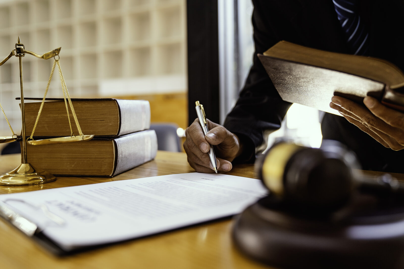 A legal professional reviewing printed documents beside a gavel on a desk